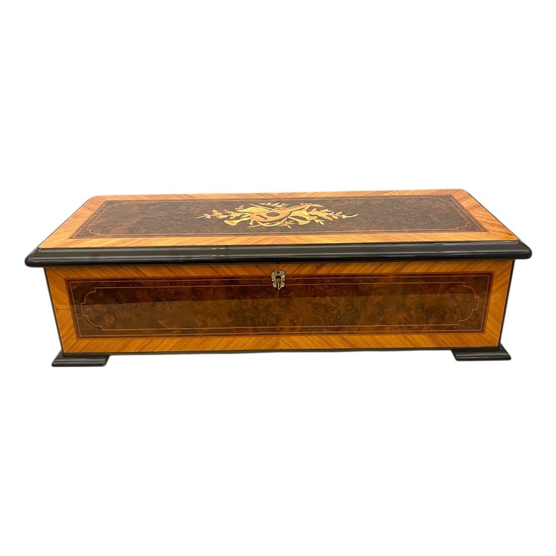 Reuge Music Grand Cartel Cylinder Music Box: Reuge Music Grand Cartel Cylinder Music Box. Wood veneer box which opens with a key. Lid has a lute and horns design. Label inside reads Reuge Music Sublime Harmonie Sainte-Croix Switzerland and lists