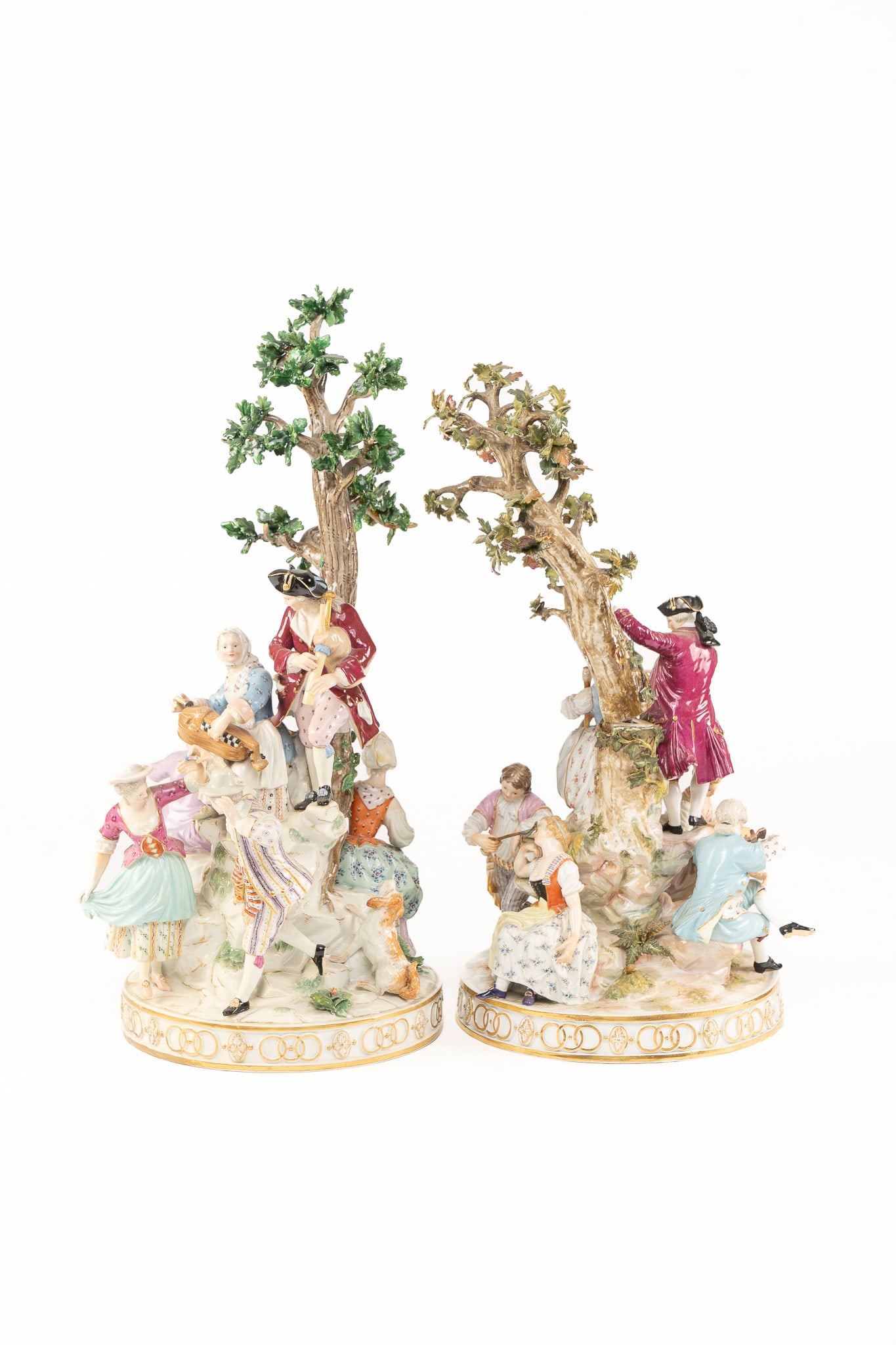 Pair of Important Large Meissen Porcelain Sculptures: A pair of large porcelain sculptures featuring trees, gentleman and ladies in play. Signed with the blue cross sword marks. Measuring an impressive H 20 W 8 D 8 inches and H 16 W 8 D 8 inches