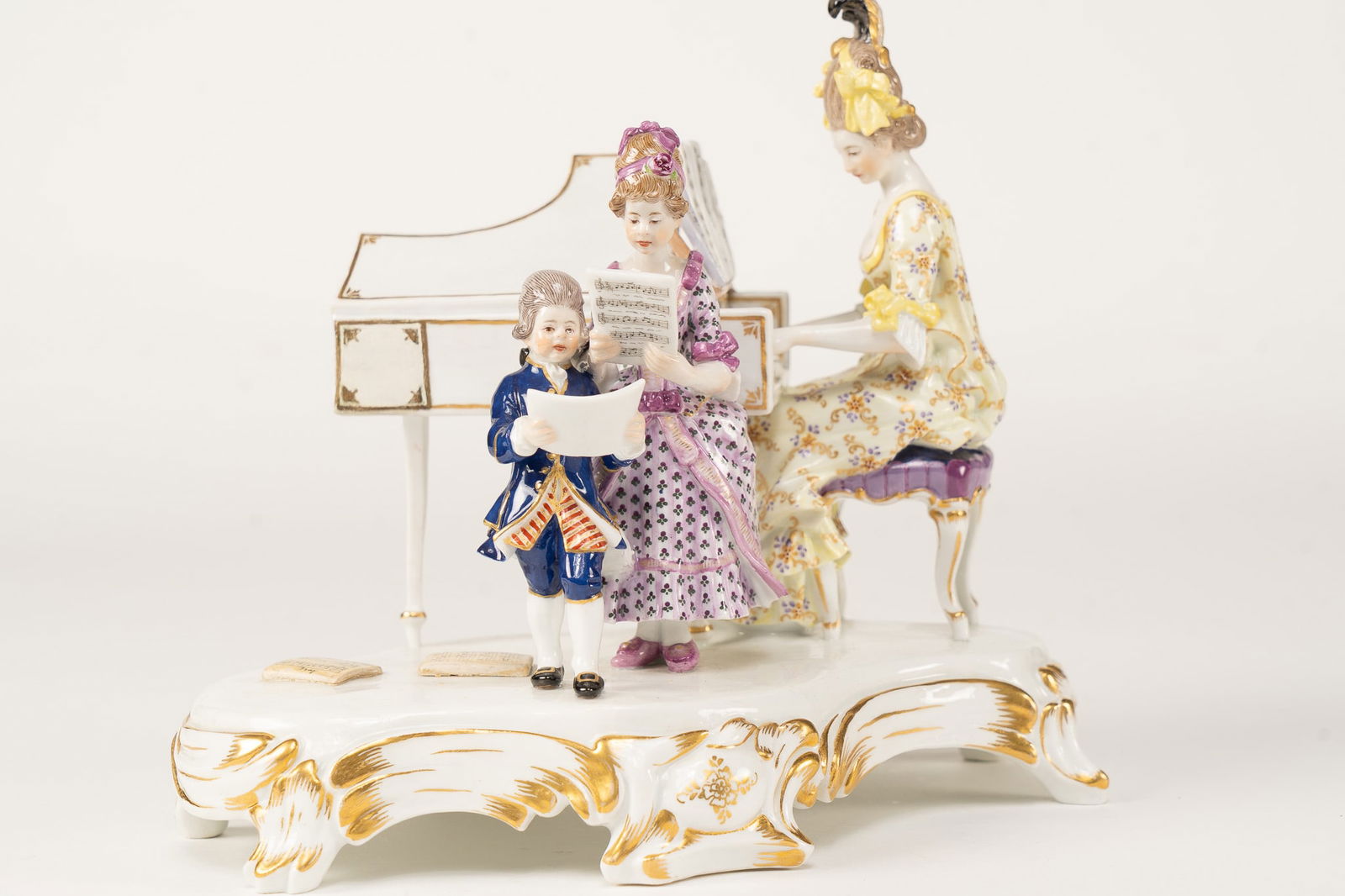 Meissen Porcelain Family Concert: A beautiful Meissen porcelain figural of a woman playing the piano and two children singing. Crossed sword marking and inscribed T 186. Measuring H 7.5 W 8 D 8 inches