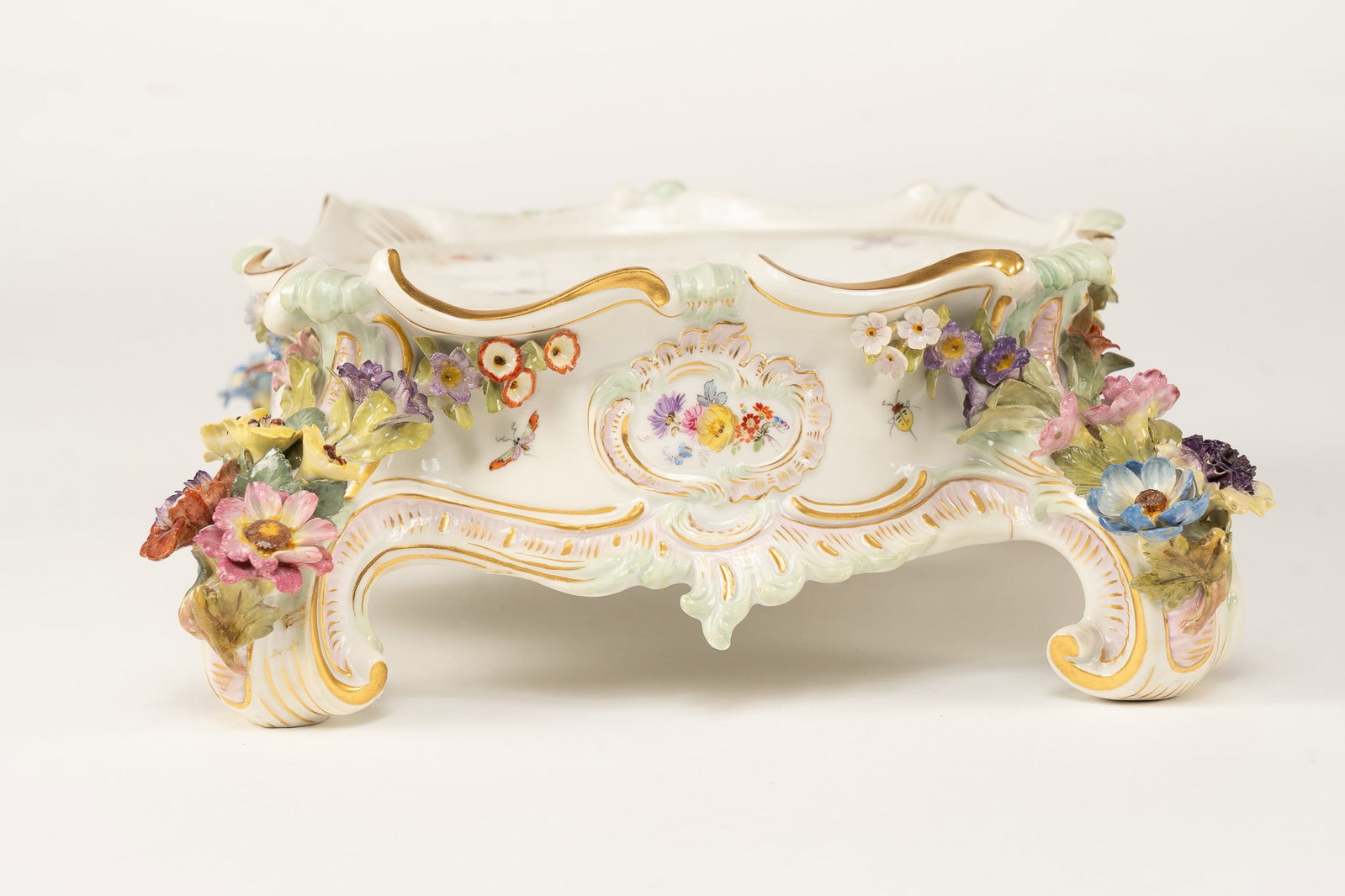 Meissen Porcelain Floral Pedestal: An incredible pedestal by Meissen. Applied flowers on four feet, painted flowers and butterflies on top. Signed with the crossed arrows market. Measuring H 4 W 10 D 10 inches