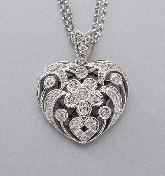 14K gold and diamond heart shaped pendant: 14K gold and diamond heart shaped pendant on a double chain, the pendant mounted with 50 diamonds, in a 14K white gold filigree mount. Chain stamped, "585 ITALY," pendant stamped, "14K 585 D.D." 5.8 g