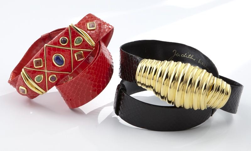 (2) Judith Leiber snakeskin belts: (2) Judith Leiber snakeskin belts comprising (1) red snakeskin belt with a red enameled and cabochon inlaid buckle, 30''L, and (1) black snakeskin belt with gold tone shaped buckle, 34.25''L. Circa -