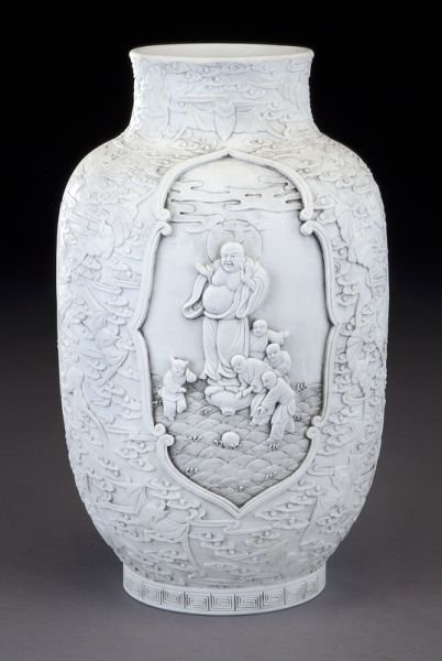 Chinese Qing white porcelain vase in high relief: Chinese Qing white porcelain vase in high relief depicting figures and boys in a medallion, surrounded by modeled bats and clouds. Spurious six character Daoguang mark to base. 10.5"H, Circa - Late 19