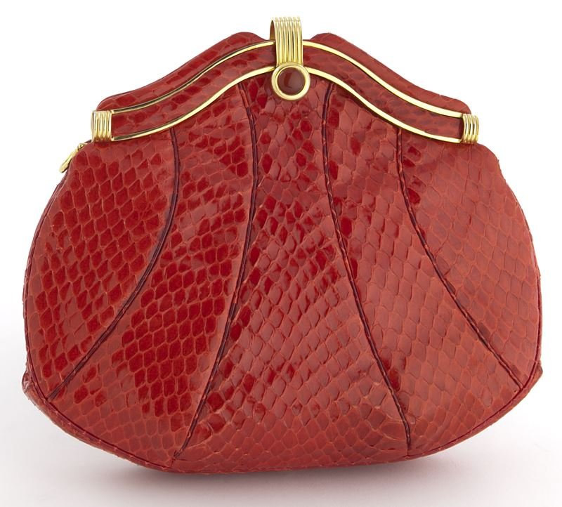 Judith Leiber red snake skin clutch: Judith Leiber red snake skin clutch with gold tone and red cabochon hardstone clasp to the upper rim, change purse, mirror, comb and strap concealed within, labeled Judith Leiber to the interior. 8" H