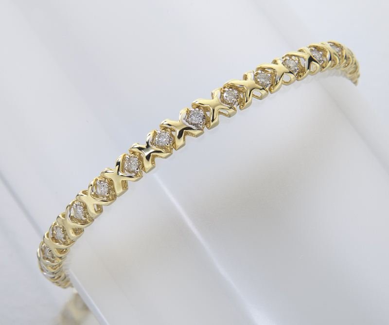 14K gold and diamond line bracelet: 14K gold and diamond line bracelet mounted with 30 round brilliant cut diamonds, mounted in 14K yellow gold with an X and O design. Stamped, "14K." 11.5 grams. Provenance: The estate of a Gentleman, D