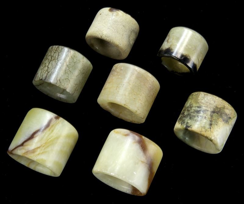 (7) Chinese carved jade archer's rings,: (7) Chinese carved jade archer's rings, the exterior walls carved in low relief depicting archaistic motifs and symbols of bagua trigrams or sacred animals. Provenance: From the collection of a promin