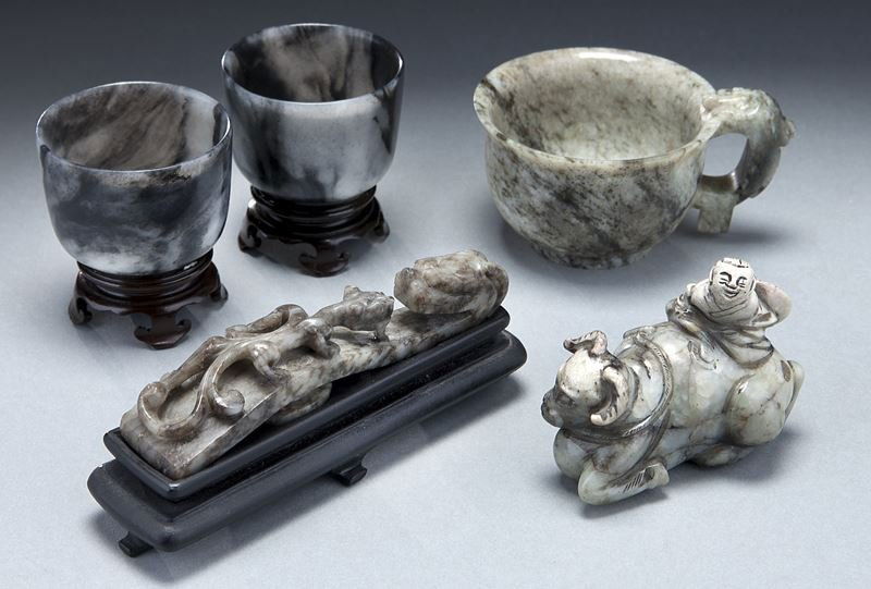 (5) Chinese Qing grey jade carvings.: (5) Chinese Qing grey jade carvings. (1) pair of cylindrical form cups, on floriform hardwood stands; (1) small libation cup with everted rim and dragon form handle; (1) depicting a boy riding on a re