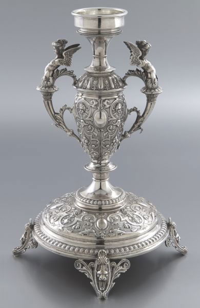 German Wollenweber silver figural candlestick,: German Wollenweber silver figural candlestick, the amphora form body with repousse scroll and floral decoration supported the candle holder and flanked by winged female form handles, the round footed