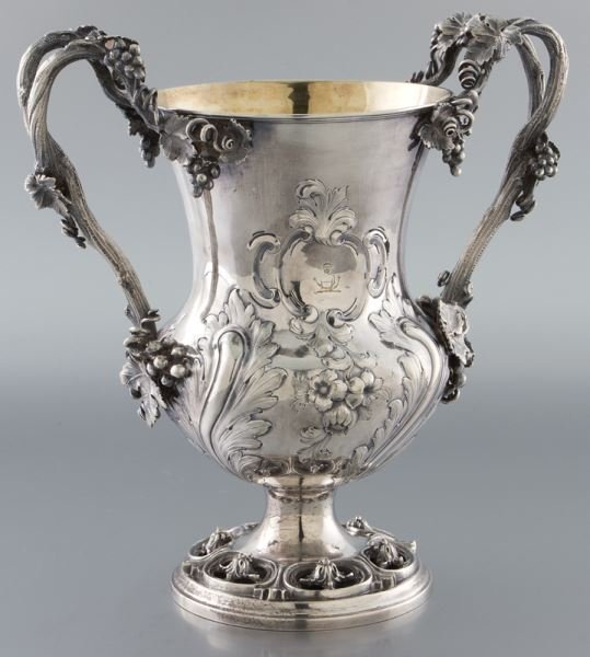 Elkington silver plate trophy cup: Elkington silver plate trophy cup hand chased with a floral and foliate motif to the body and armorial emblem engraved to the center, naturalistic grapevine handles to each side, gilt interior. Marked