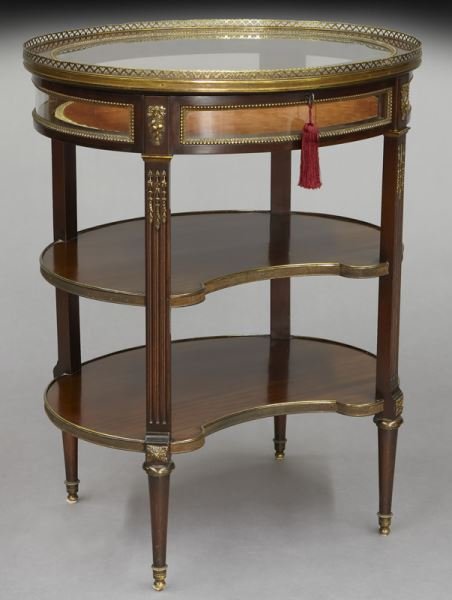 French oval vitrine with bronze mounts and key,: French oval vitrine with bronze mounts and key, the beveled glass top surrounded by pierced gallery over two shaped shelves supported by fluted tapered legs. 31"H x 24.25"W x 19.5"D, Circa - 1900-1925