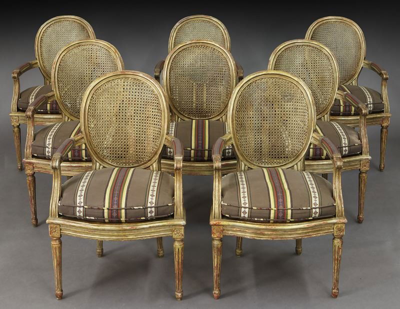 Set of 8 French painted and caned armchairs: Set of 8 French painted and caned armchairs with cushions, rounded back and shaped seat rail joined by arms ending in scrolled handholds, supported by fluted circular legs. 37.5"H x 24.5"W x 18"D, Cir