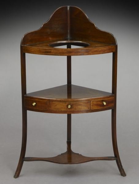 Georgian mahogany corner washstand: Georgian mahogany corner washstand with cutout for bowl and pitcher set, one drawer and two false drawers with string inlay, shaped lower stretchers on front splayed legs. 40.25"H x 16" Sq., Circa - 1