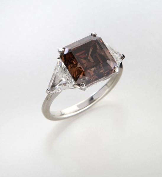 18K, fancy dark orange-brown diamond ring (GIA),: 18K, fancy dark orange-brown diamond ring (GIA), 6.10 cts., with the central square emerald (asscher) cut dark orange-brown diamond, flanked by a pair of triangle brilliant cut diamonds, 2.0 cts. appr