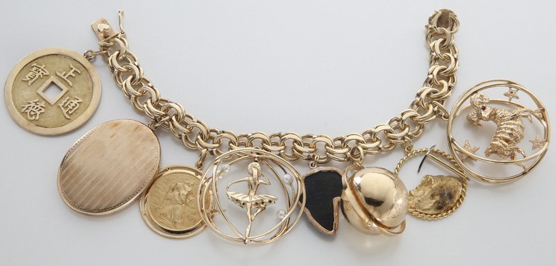 14K gold charm bracelet: 14K gold charm bracelet with charms including a locket, a ballerina, a globe and an 18K gold Saint Christopher medal, among others. Stamped or tested 14K. 134.9 grams. 7.5"L, Circa - 20th C.