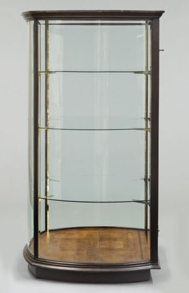Mahogany curved glass display cabinet: Mahogany curved glass display cabinet with glass top and molded cornice over three curved glass sides and flat glass door to front, three glass shelves to interior. 66"H x 39"W x 36"D, Circa - Late 20