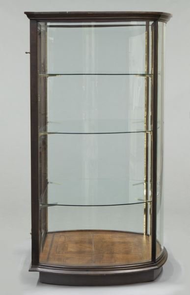 Mahogany curved glass display cabinet: Mahogany curved glass display cabinet with glass top and molded cornice over three curved glass sides and flat glass door to front, three glass shelves to interior. 66"H x 39"W x 36"D, Circa - Late 20