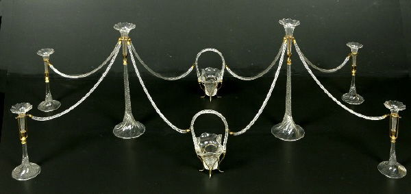 A monumental glass centerpiece having two tall: central epergnes and two small handled baskets, all with connecting spirally turned glass rods hooked into four smaller epergnes. 16 pieces total. 20.25"H x 65"W, Circa - 1900.