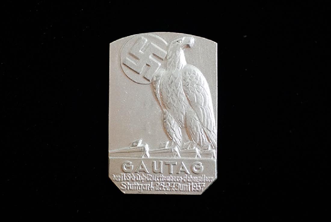 WWII German 1937 'Gautag der NSDAP-Wurttemberg': WW2 German 3rd Reich tinnie dated 1937; 27 x 40mm gray aluminum pin-back; maker marked reverse; excellent condition.
