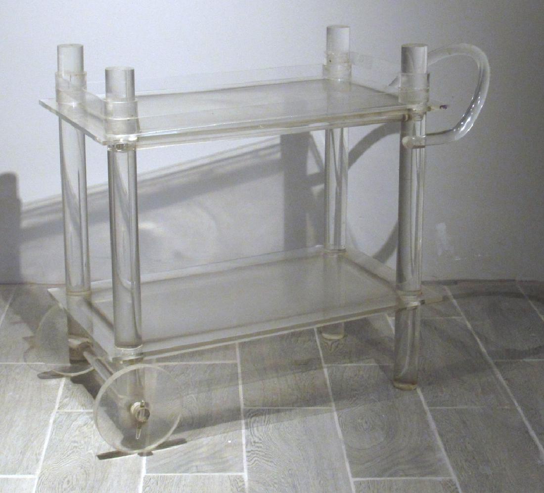 Mid Century Lucite Rolling Tea/Bar Cart: 2 shelves (showing age) with top having removable gallery. Sculpted handle and tubular posts, wheels working. 37"w X 16"d X 28"h. (From a Central Park West Estate)