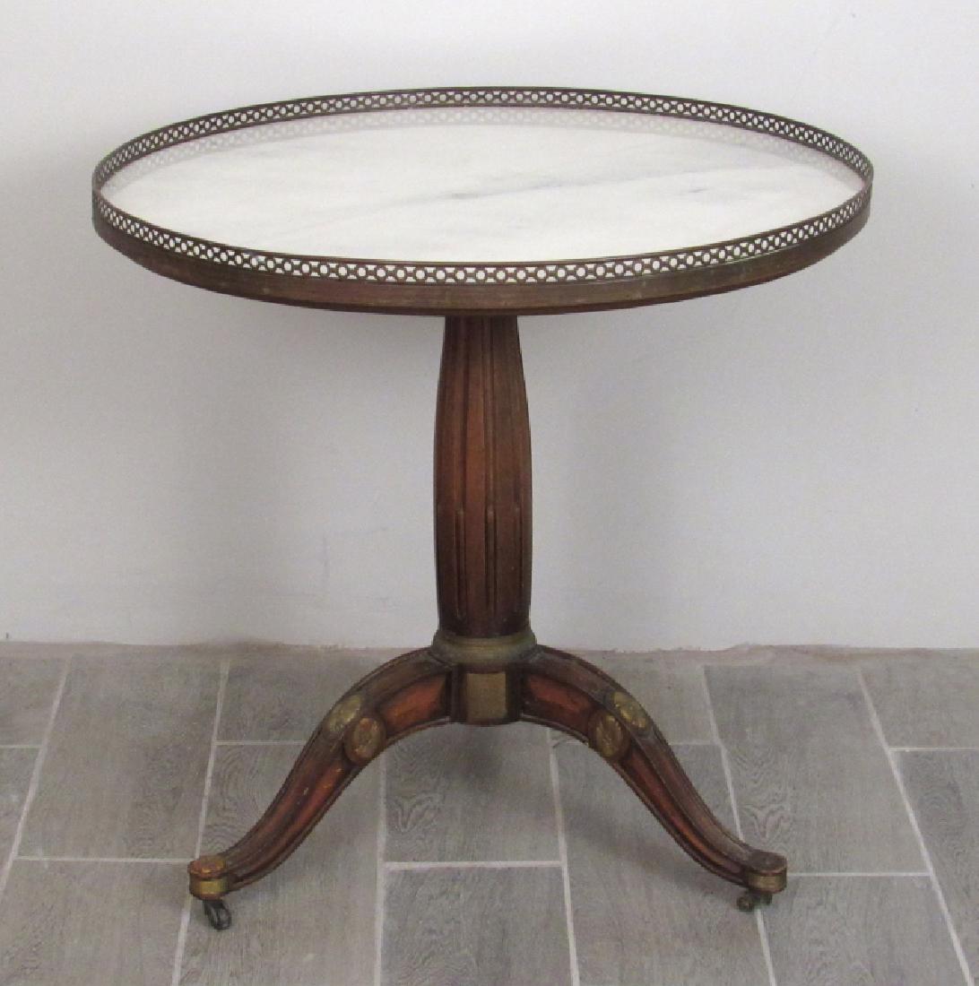 Louis XVI Style Gueridon: Marble top with pierced brass gallery. Fluted post on tripod base. Lose casters. 28"D by 28"H.