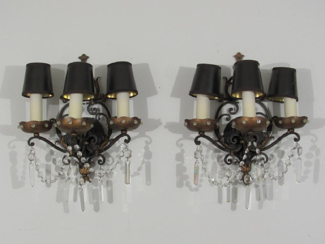 Pair House of Jansen Style Sconces: Wrought iron backs, with tole bobeches having crystal button inserts. Crystal button chains and prisms, 3 arms each, paper shades. 16"w X 20"h X 10"d.