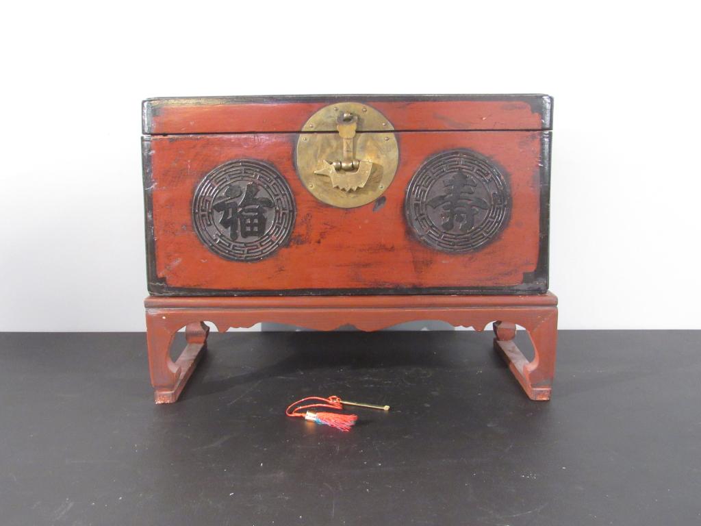 Chinese Red Lacquered Chest on Stand: Red and black lacquer incised and painted chest with brass lock and key. 23.25"W X 17.25"H X 12"D. (East 57 Street Estate)