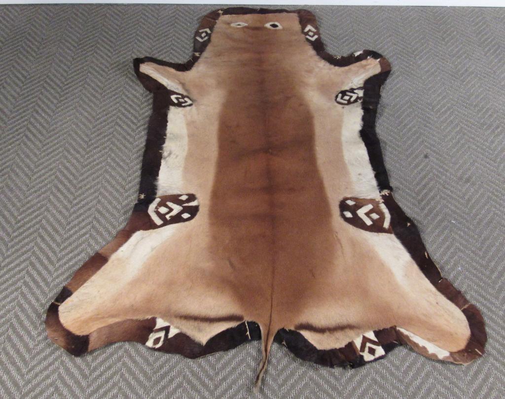 Stitched Animal Skin Rug: Single animal pelt stitched and decorated with eyes and symbol designs. Two tears to the back. 60" X 46"