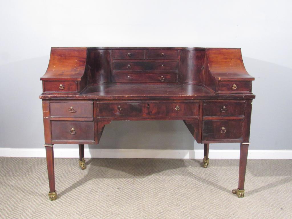 Carlton House Style Mahogany Desk: Demi-line with side slopes, all around doors and drawers. Gadroon back edge. Brass castors adapted from a dining table. Needs refinishing. Nicks and scratches. 54"W X 29"D X 40"H.