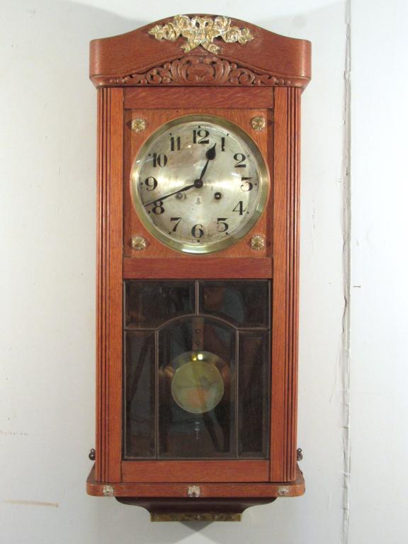German Oak Hanging Wall Clock: Gilt metal mounts with metal face signed GB, pendulum and 2 keys. Side balances. Convex glass above leaded beveled glass door. 13" X 7" X 31"h (A North Salem, NY Estate)
