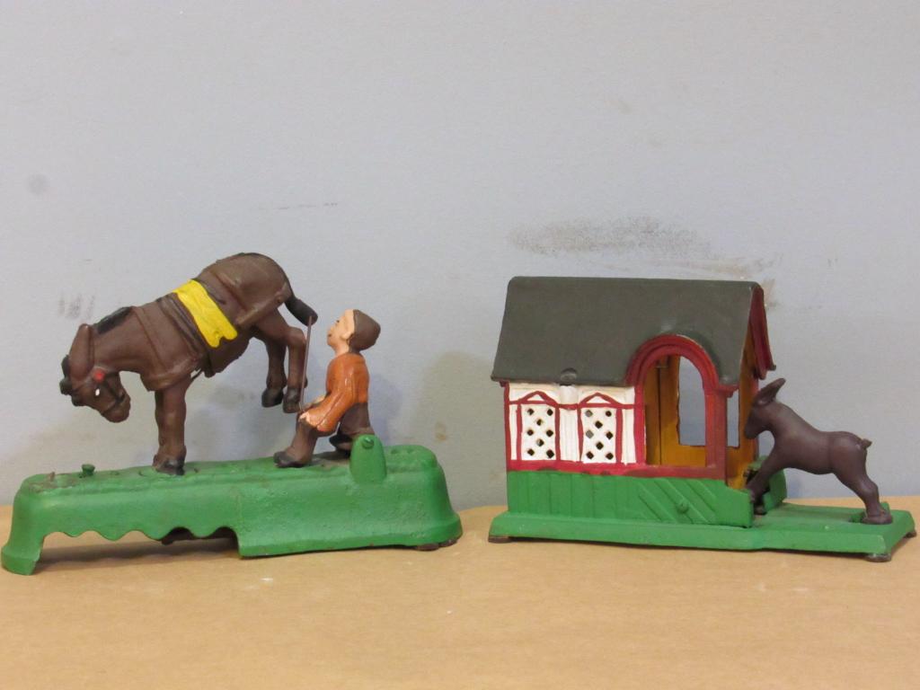 2 Reproduction Iron Painted Banks: 1 depicts donkey kicking back legs into character. 1 depicts donkey going into stable(does not function). Made in Taiwan. Tallest: 9.5" x 2.5" x 6.5"