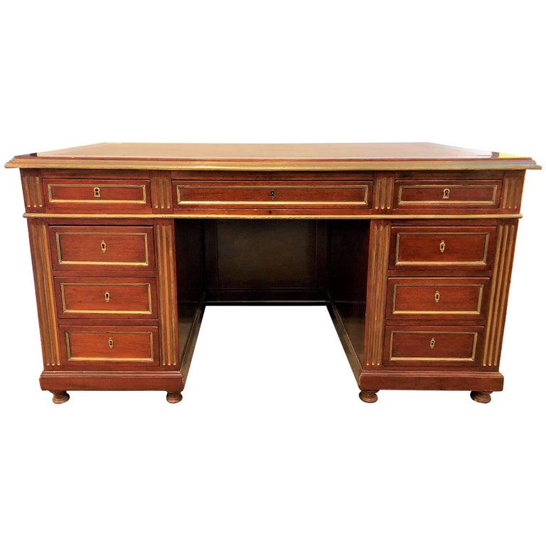 Russian Neoclassical Desk with a Leather Top: A 19th or early 20th century Russian neoclassical desk having a tan leather top. The center top drawer flanked by a pair of side drawers with three drawers under each side. This Greenish tan colored l