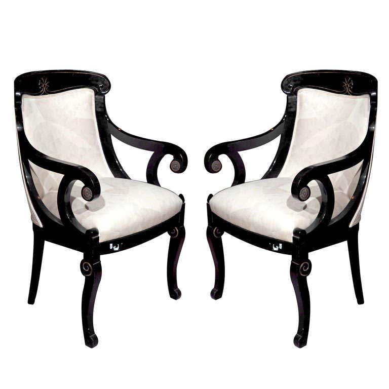 Pair of Hollywood Regency Style Ebonized Armchairs: Pair of Napoleon style ebonized fauteuils, 20th century, each with domed back and scrolled arms, padded back and seat, brass accents on tip of the arms. Height: 36 in. Width: 22.5 in.Depth: 18 in. Sea