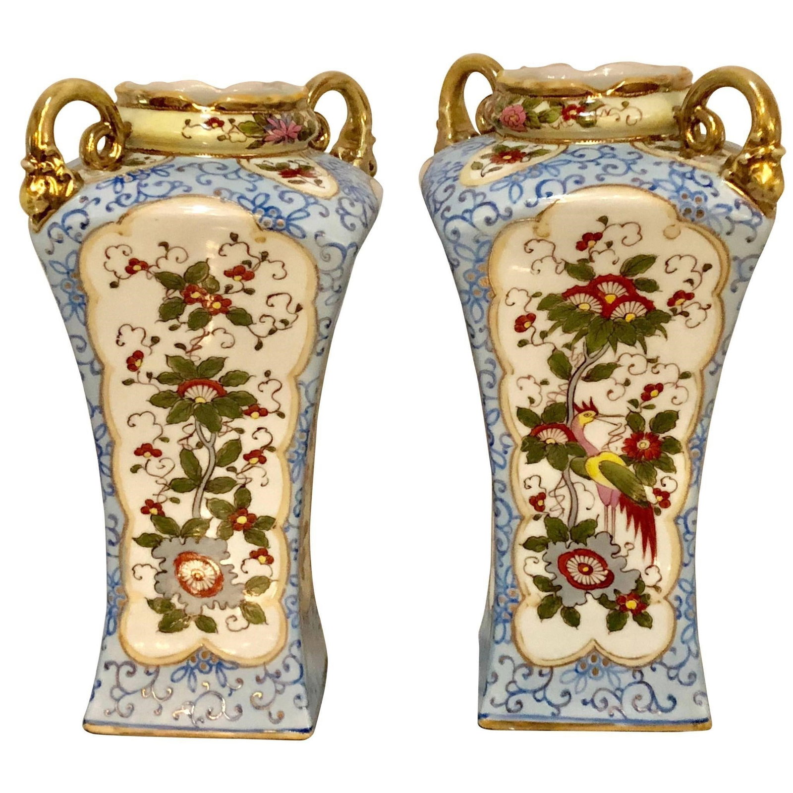 Pair of Porcelian Twin Handled Vases, Nippon: A pair of Chinese Chippendale style twin handled Nippon vases. Each of these hand-painted vases have gilt gold handles, rims and bases as well as framing to separate the finely cast design on these hi