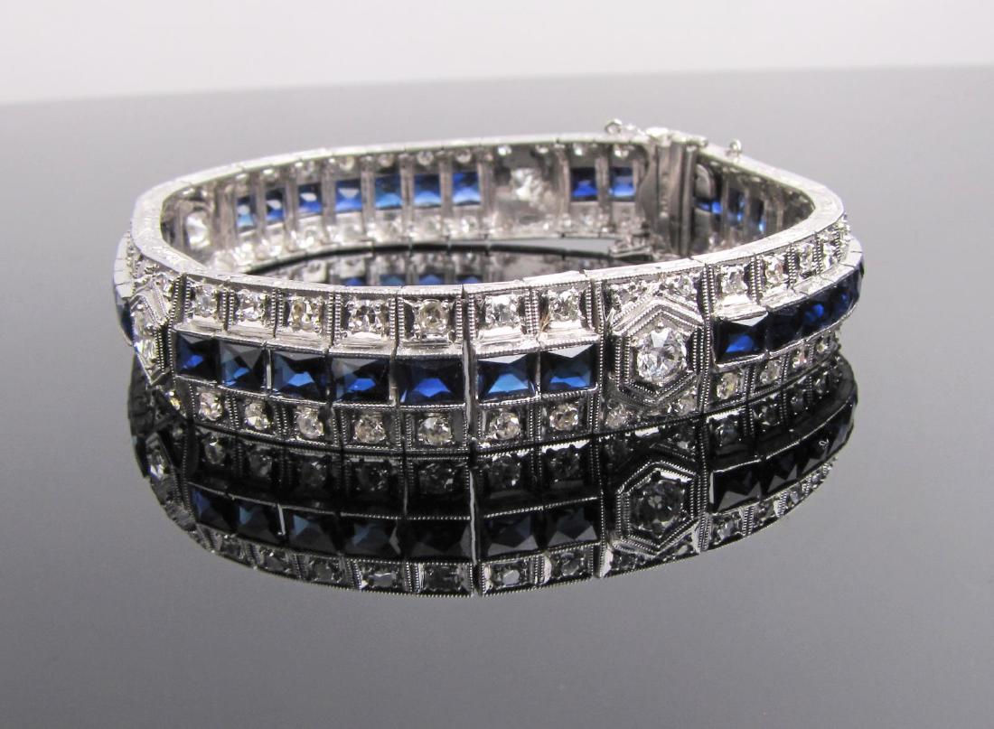 Platinum Art Deco Diamond/Sapphire Bracelet: A stamped platinum lady's hand-assembled art deco design bracelet with mil grain and engraved, bright finish, hidden safety chain, containing five bead-set, Old European cut diamonds, measuring 3.5 x 