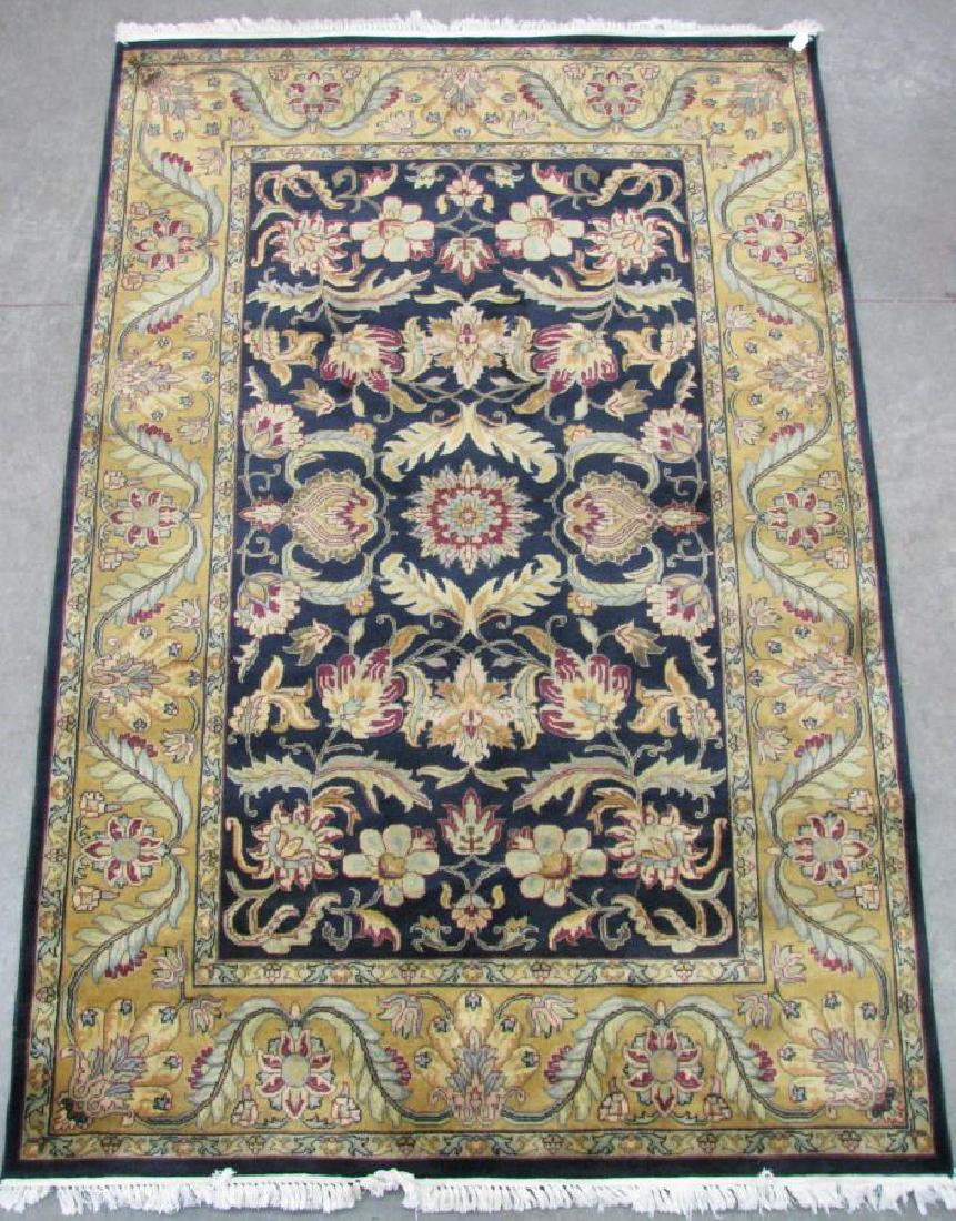 Hand Tufted India Agra Area Rug: Hand Tufted India Agra Area Rug, having a navy blue field with red and tan floral decoration, tan border with red and blue floral decoration, 8'3" x 5'5"