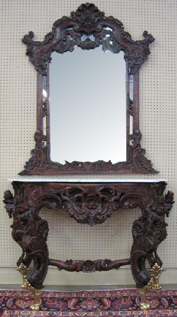 Rococo Style Mahogany Console and Mirror: An ornate, carved mahogany console with wall mirror, Rococo style, late 20th century, base with gold accents mounted on paw foot, with floral and scroll motif, marble top, (mirror frame cracked top le