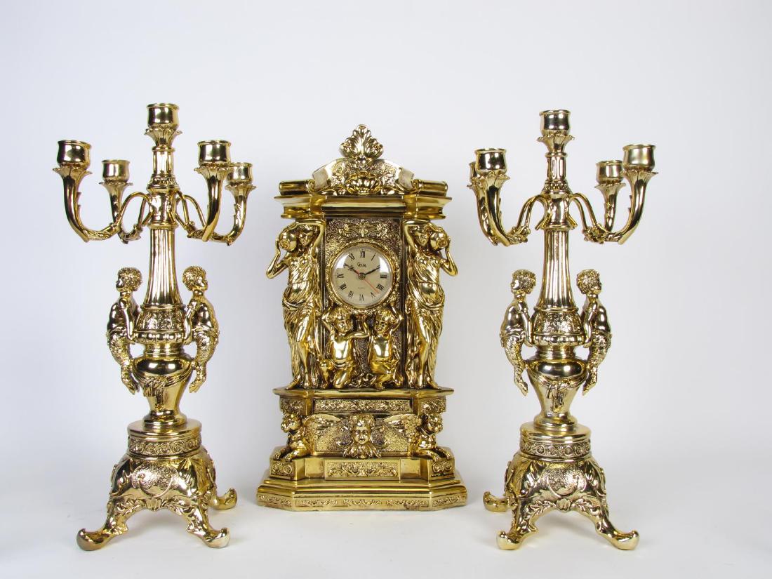 Crosa Mantle Clock and Garniture Set: Crosa Mantle Clock and Garniture Set, composite clock with gold finish, classical figure and Puti decoration, roman numeral dial, pair of Chateau Cambord five light candelabra, gold finish composite b