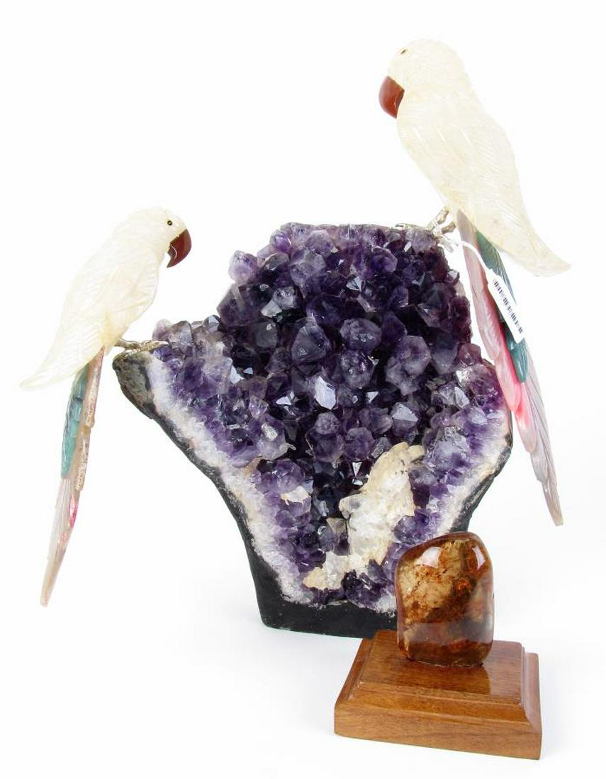 Amethyst Bird Sculpture and Amber Specimen: Two stone decorative items including a 14.25" high figural grouping with two stone carved parrots mounted atop a amethyst geode base; and a natural amber specimen mounted to carved wood base, 3.75" hi