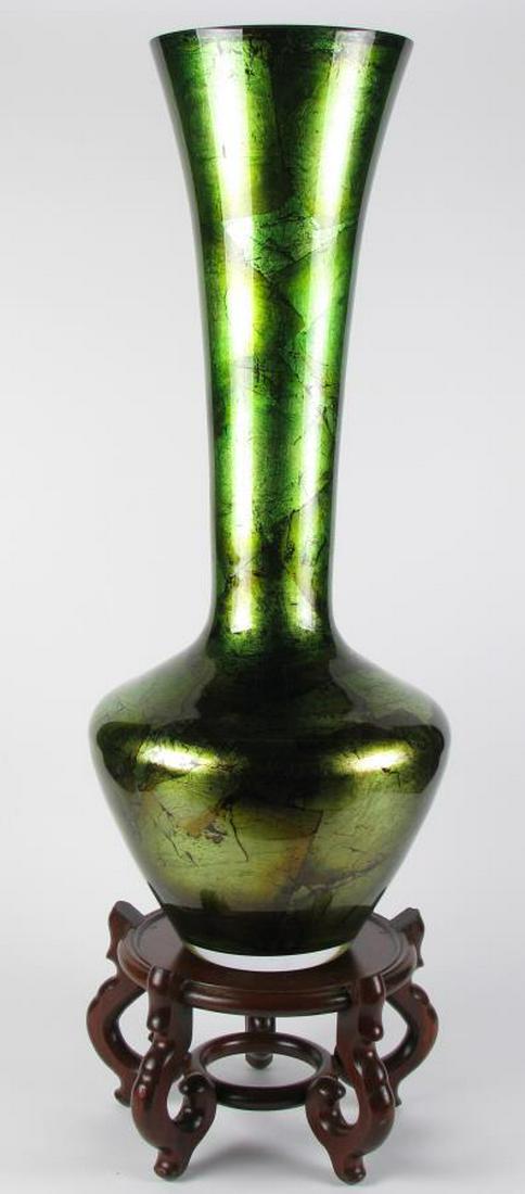 Glass Floor Vase on Wood Base: A green glass floor vase with metallic finish, long neck with flared rim, 33" high, on carved wood base