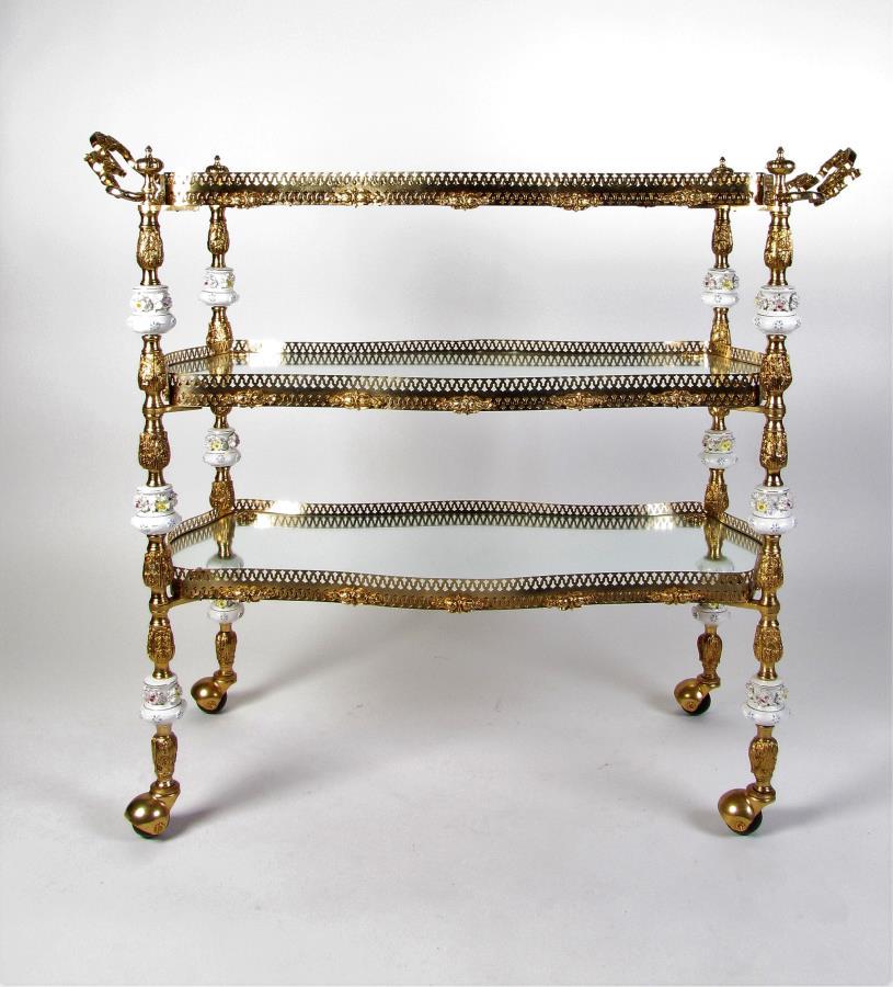 Mirrored and Brass Three-Tiered Tea Cart: A mirrored and brass three-tier tea cart with floral decorated porcelain accents, pierced gallery, double handles, casters, 41" x 18" x 36"