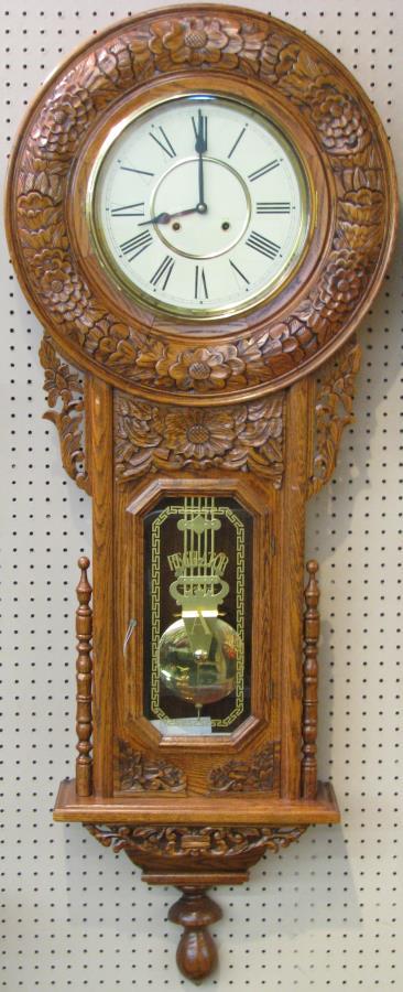 Oak Regulator Wall Clock: A Regulator type wall clock, 20th century, with pressed-carved oak case, brass pendulum, reverse painted glass door, Roman numeral dial, 22 x 58"h