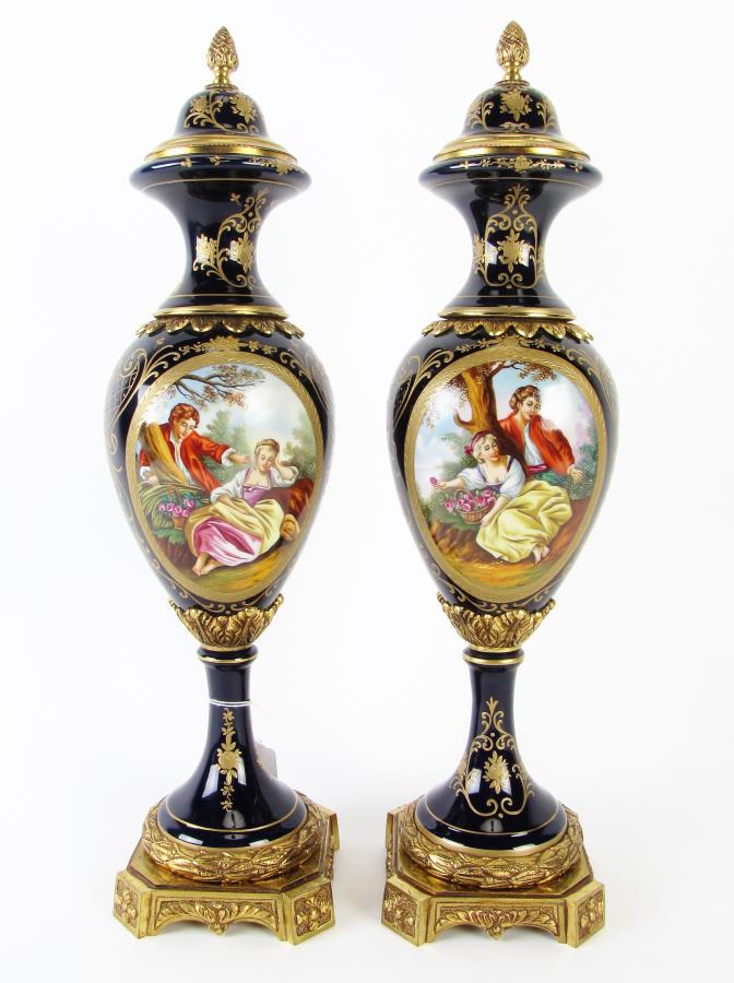 Pair of Spanish Porcelain Decorative Urns: A pair of Spanish decorative urns, cobalt porcelain bodies with hand painted romance scene, artist signed Pedro, gold enameled floral and musical instrument decorations, cast metal ormolu, hallmarked 