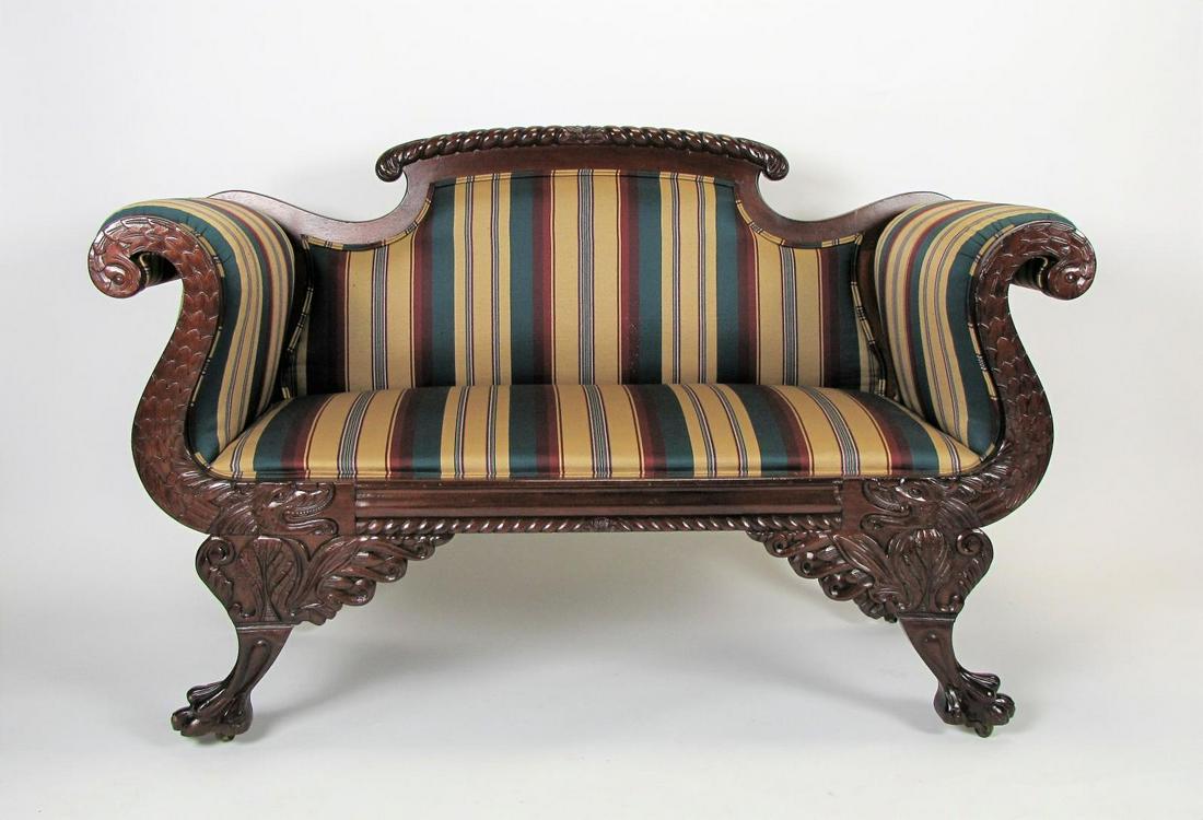 Ornately Carved Settee: An ornately carved, wood frame settee, with dragon motif carvings, three-toed paw foot with brass casters, striped upholstery, ca late 20th century, 56 x 23 x 36"h
