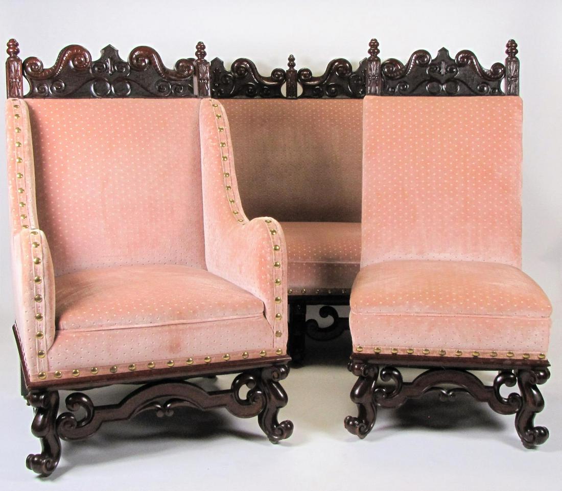 Three Piece Rococo Style Parlour Suite: A three-piece, Rococo style parlour suite, including settee, arm chair and side chair, oversized nailhead trim, open carved frames, rose color upholstery, rollers mounted to bottom of legs, 20th centu