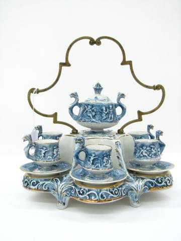Capodimonte Demitasse Set In Carrier: Capodimonte Demitasse Set In Carrier 14" in diameter, including six demitasse cups and saucers, double handled sugar bowl with lid, all in a porcelain carrier with cast metal handle
