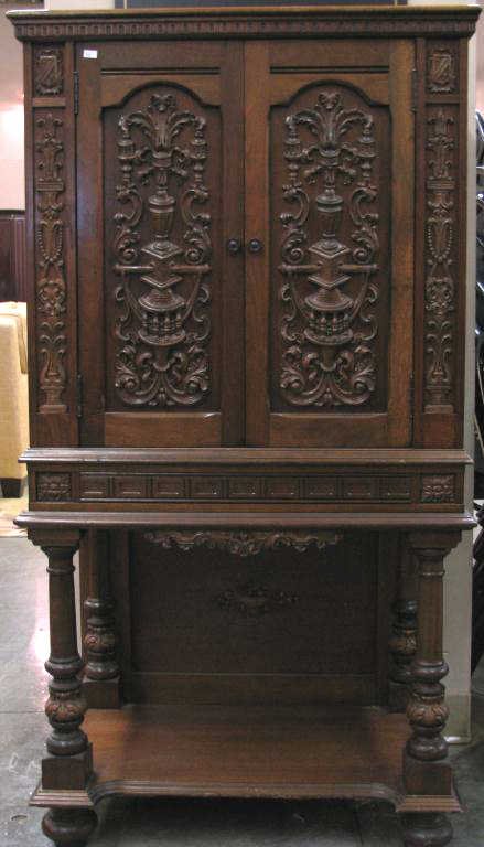 Vintage English Tudor Style Music Cabinet: Vintage English Tudor-style walnut music cabinet, with ornate applied carvings, double doors with shelf below, 52.5h x 27.5w x 16