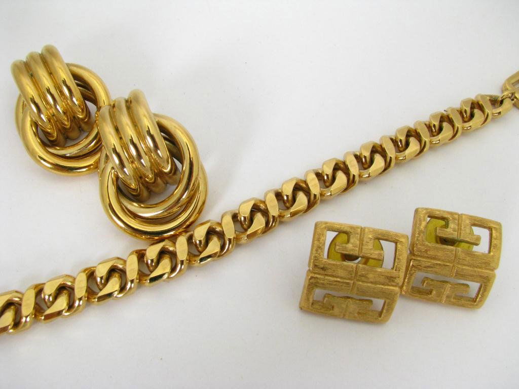 Three Givenchy Costume Jewelry Items: Three pieces of vintage Givenchy costume jewelry consisting of: 7" heavy link gold tone logo clasp 3/8" wide bracelet, pair of 1" x 3/4" cut out logo clip back earrings and a pair of 1 3/4" x 1" gold