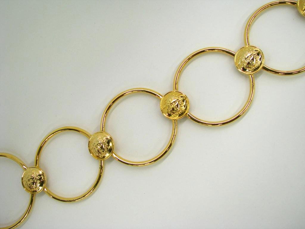 Gianni Versace Vintage Hip Slung Belt: Gianni Versace vintage circle link hip slung belt with medusa head detail. Each circular link is 2" in diameter, chain link at end to adjust fit. 33" long