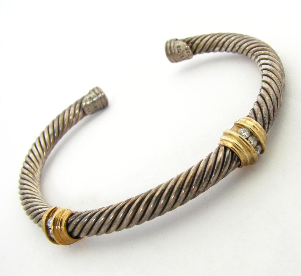 David Yurman Sterling, 18K YG Bangle Bracelet: David Yurman sterling and 18K yellow gold 3 mm bangle cable bracelet with two diamond stations. Each yellow gold station is set with four small round diamonds. Hallmarked at both ends DY 925 750