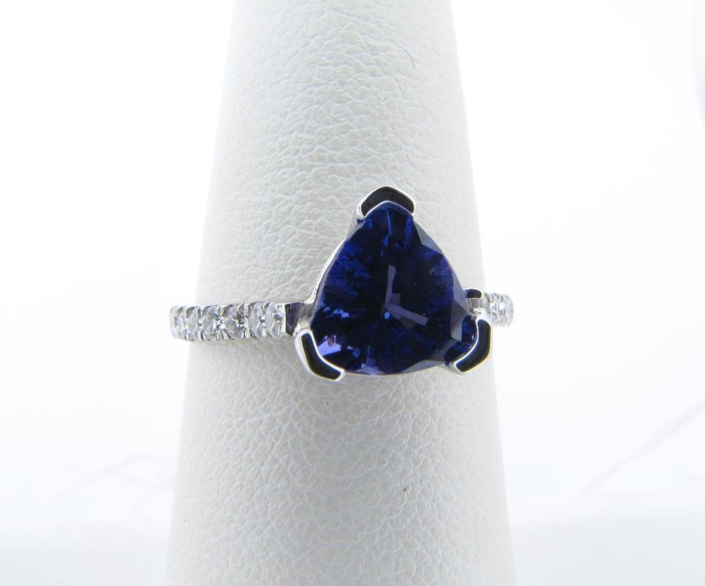 18K White Gold Tanzanite and Diamond Ring: An 18K white gold ring with trillion shape 1.4ct tanzanite center accented by sixteen round brilliant ideal cut diamonds of G color/SI clarity na